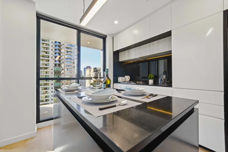 Apartment dining area beside a balcony overlooking Melbourne buildings